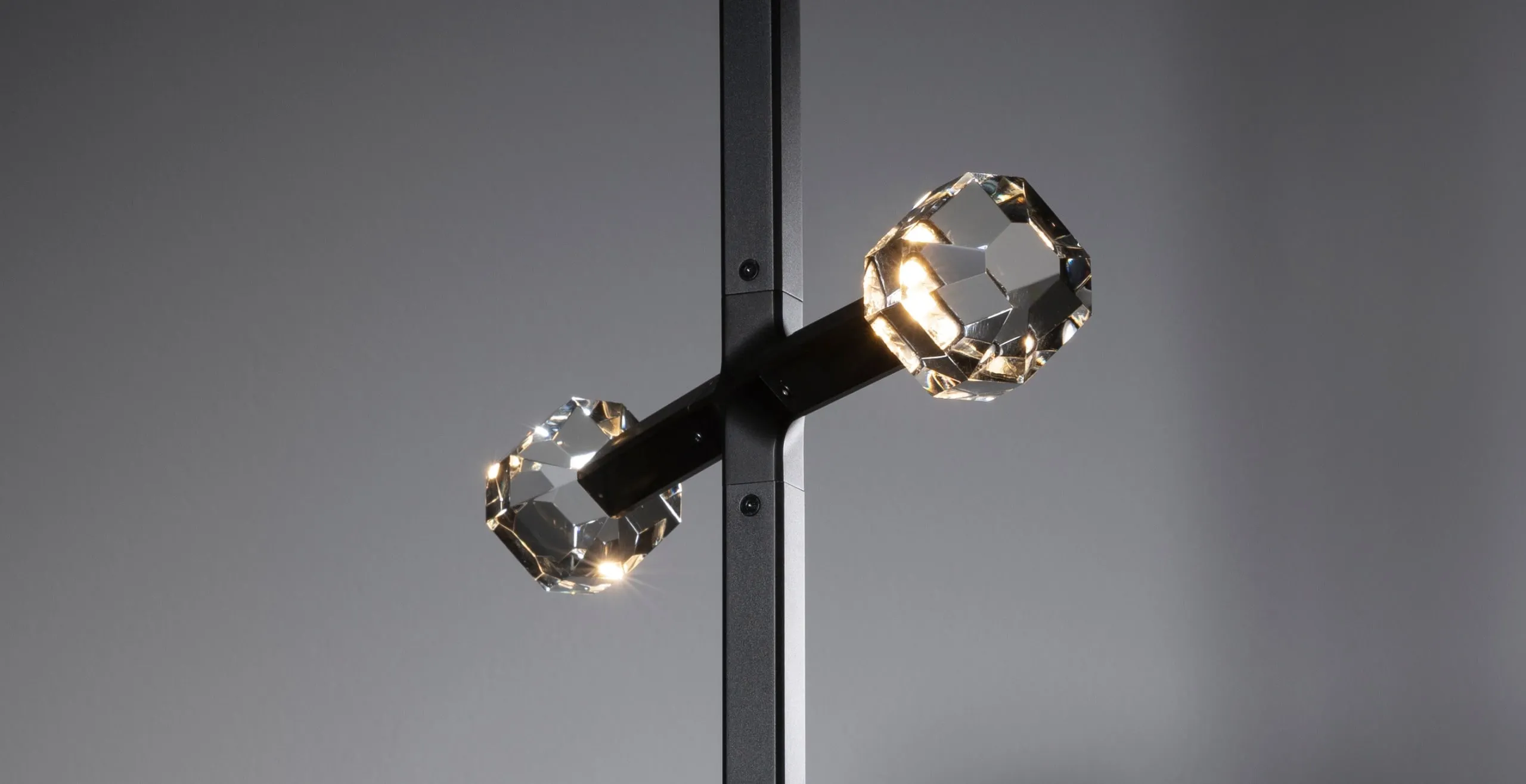 A JOULLE crystal stone at the end of an arm, lit, against a grey wall