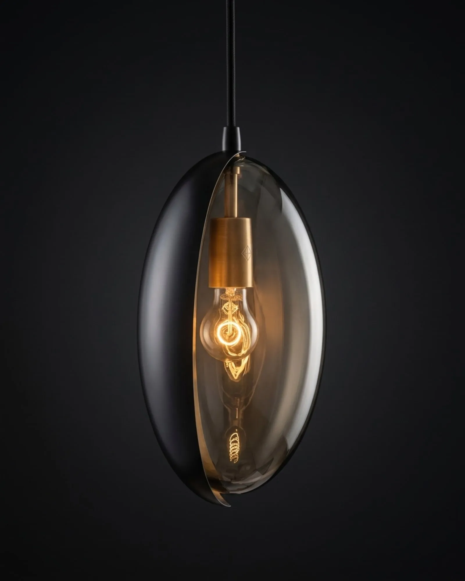 An Oona pendant in smoke glass, its eyelid turned to one side, glowing against a dark background