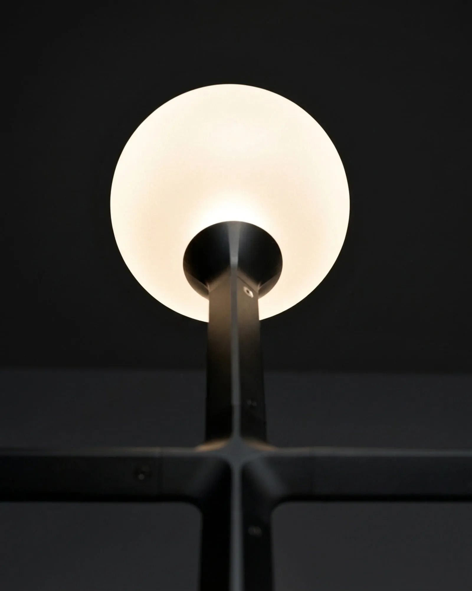A JUNIP glass globe lit from within, seen from below