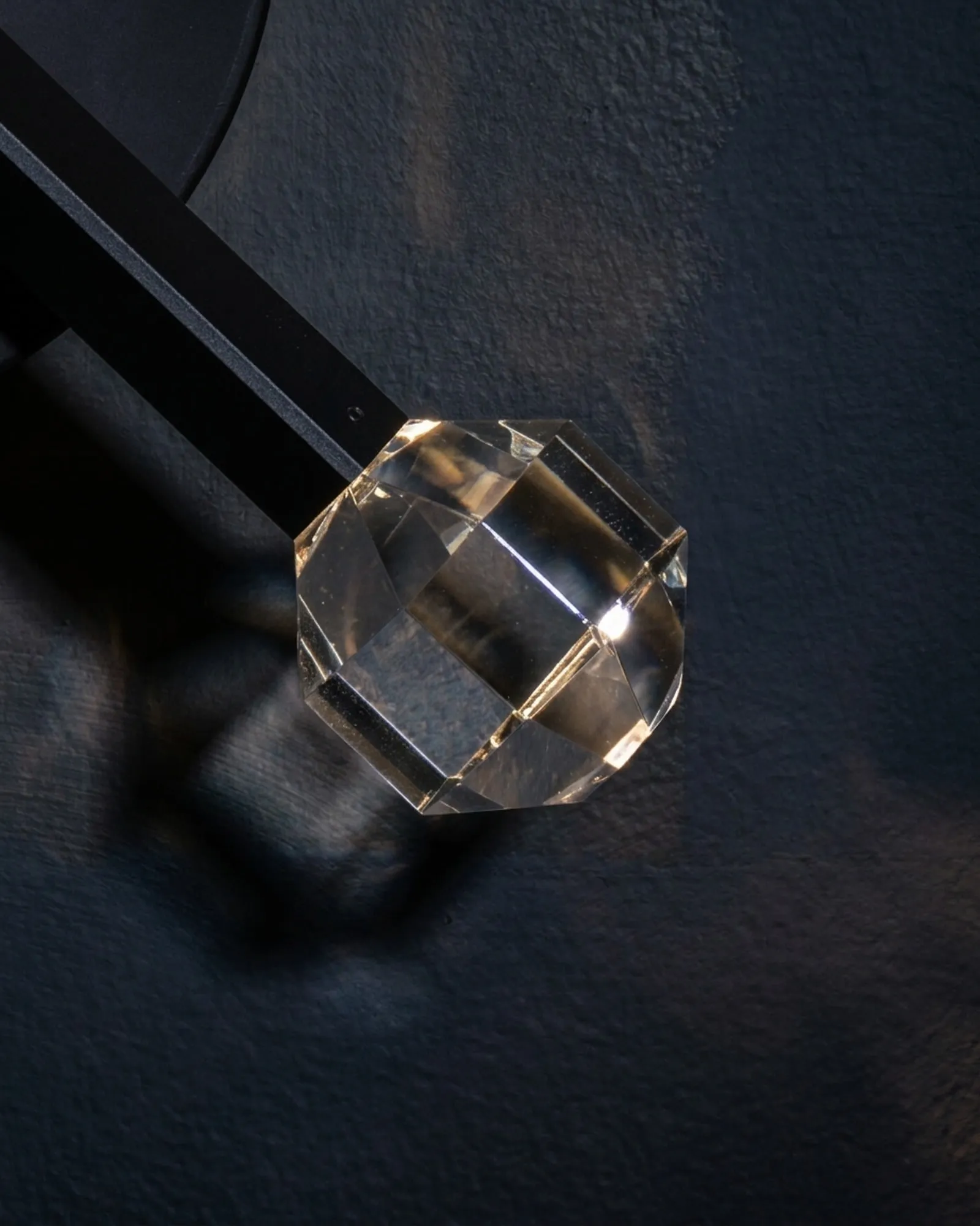 A faceted JOULLE crystal stone, close up, against a dark wall
