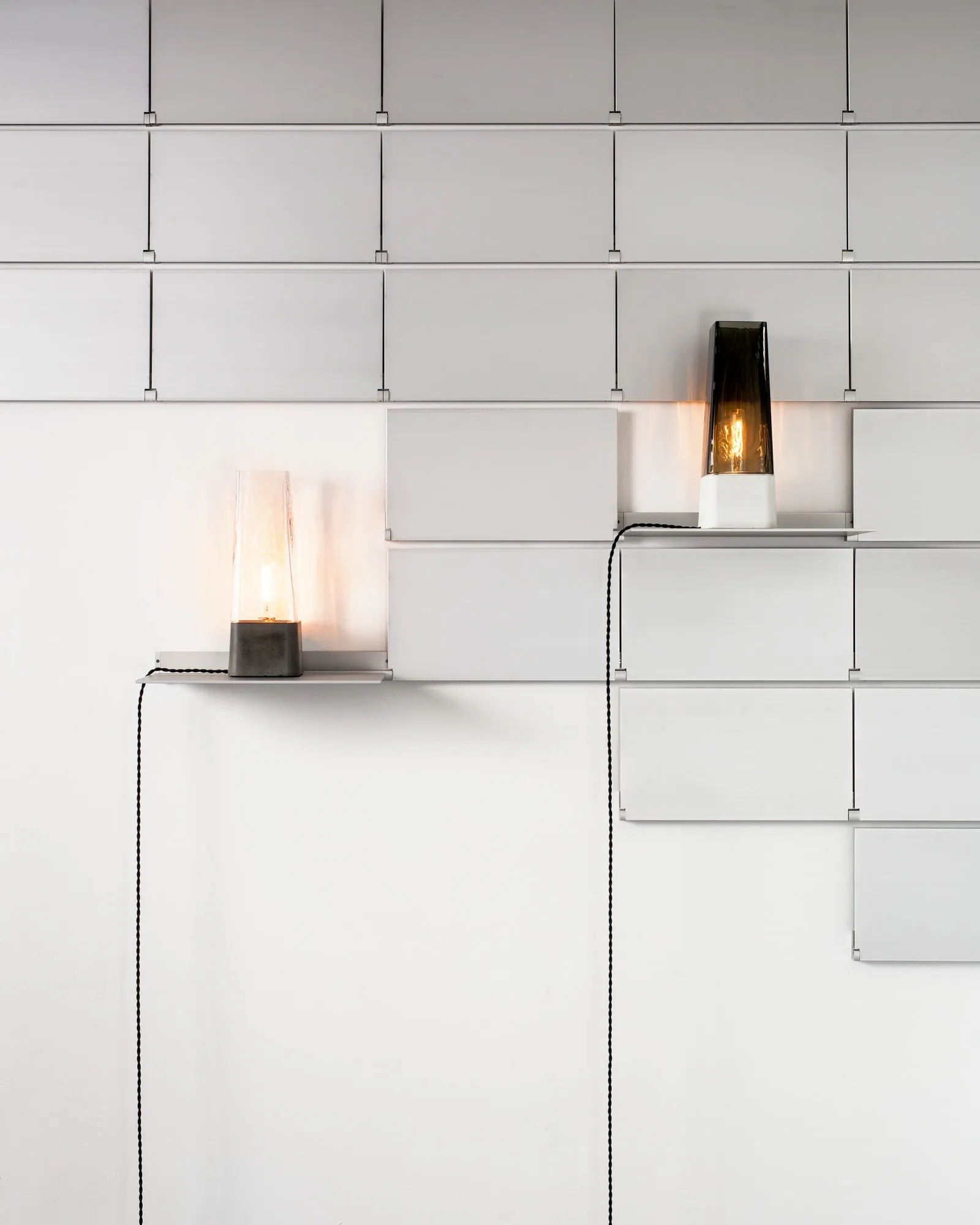 Riveli Shelves in white with two shelves down, each holding a lit lamp