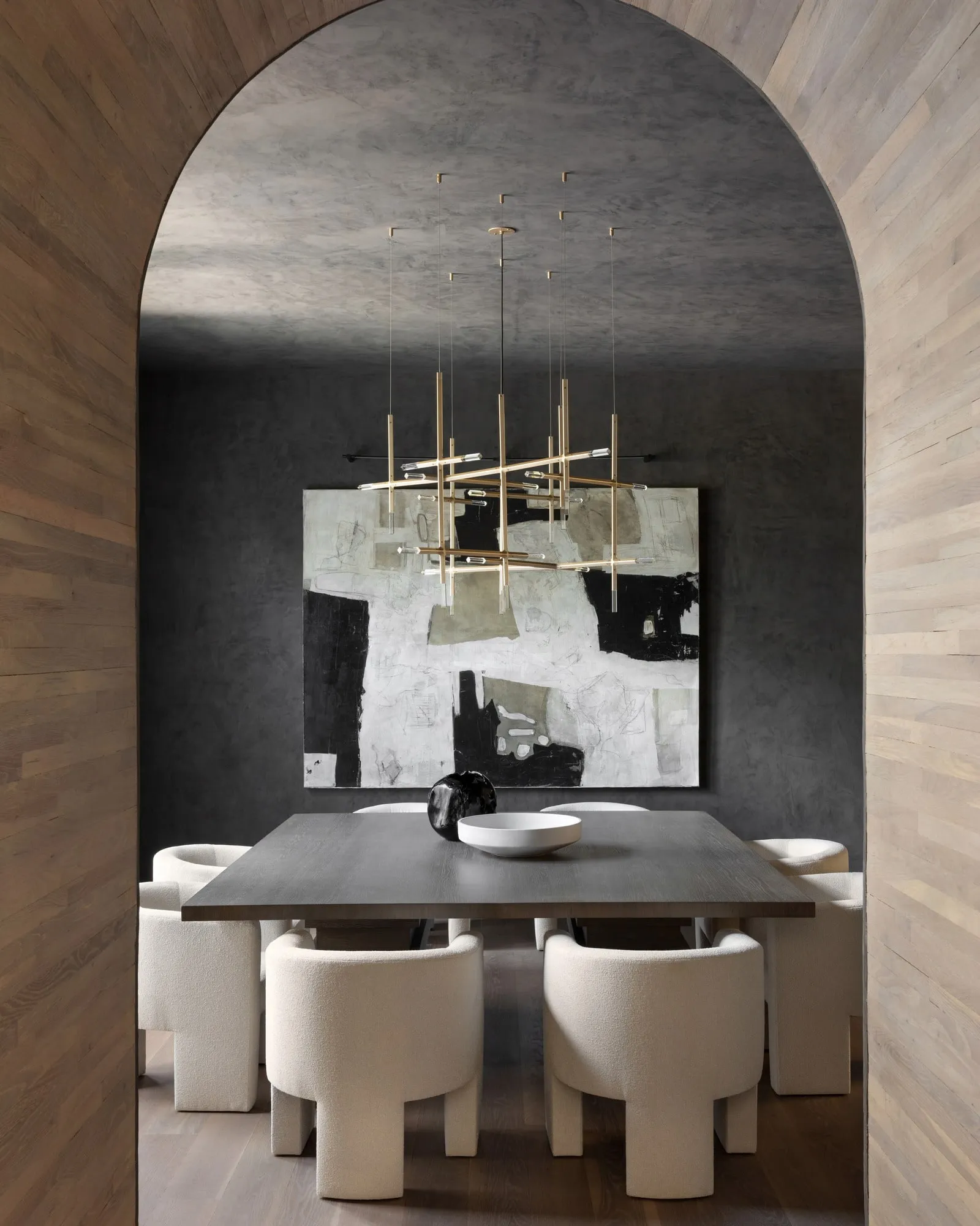 A JAX chandelier in Satin Brass over a dining table in an arched room