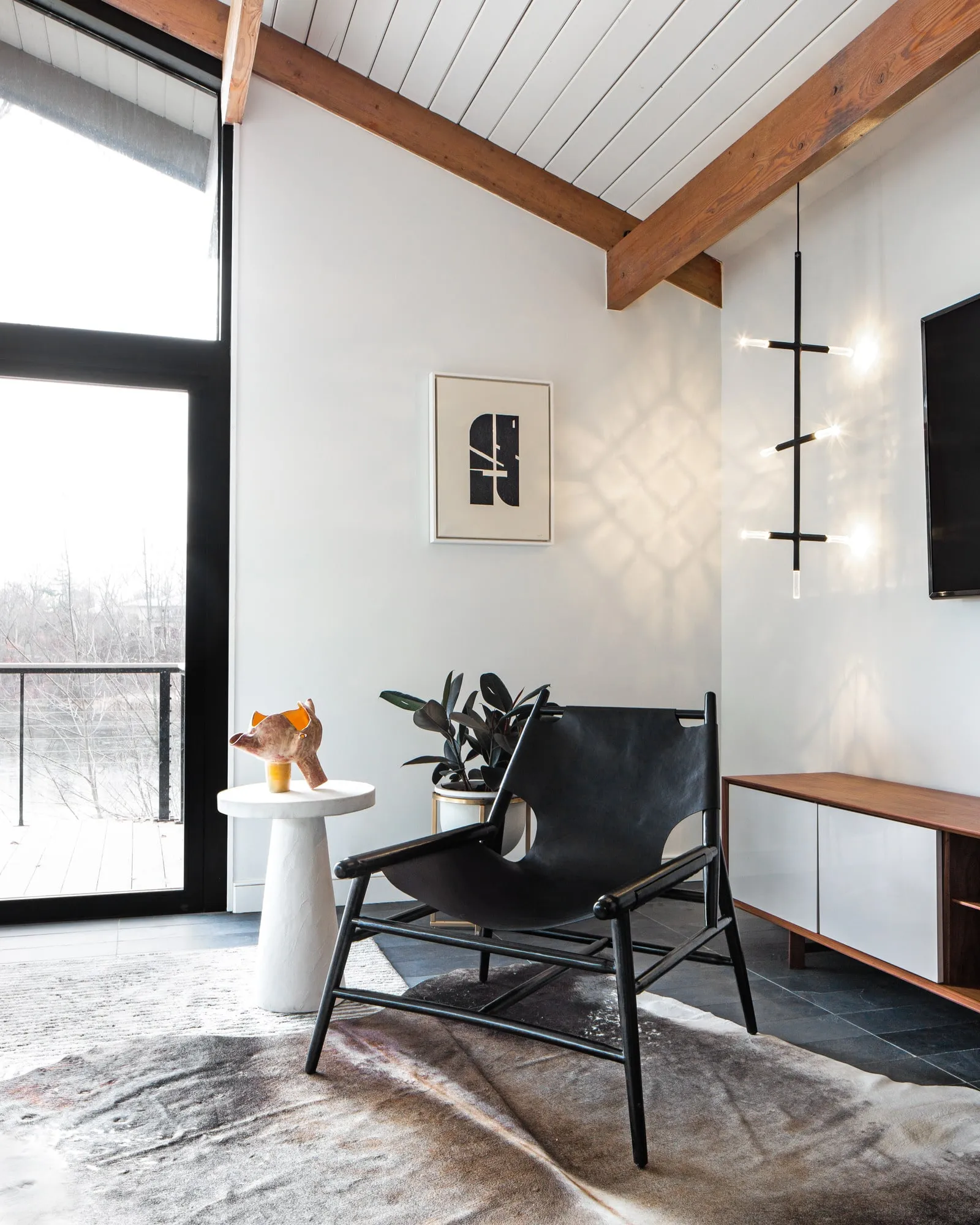 A JAX pendant beside a leather chair under a sloping white ceiling