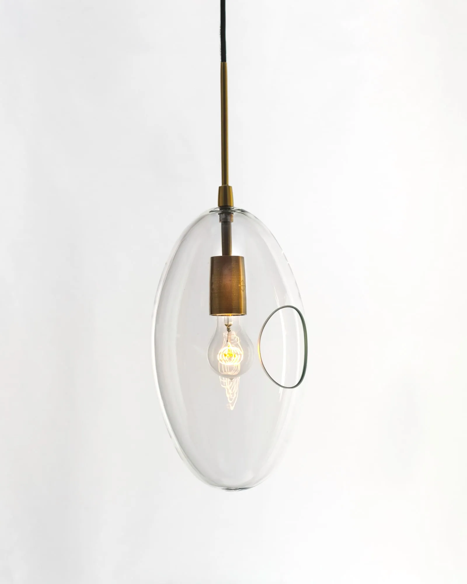 An Oona pendant in clear glass against a white wall