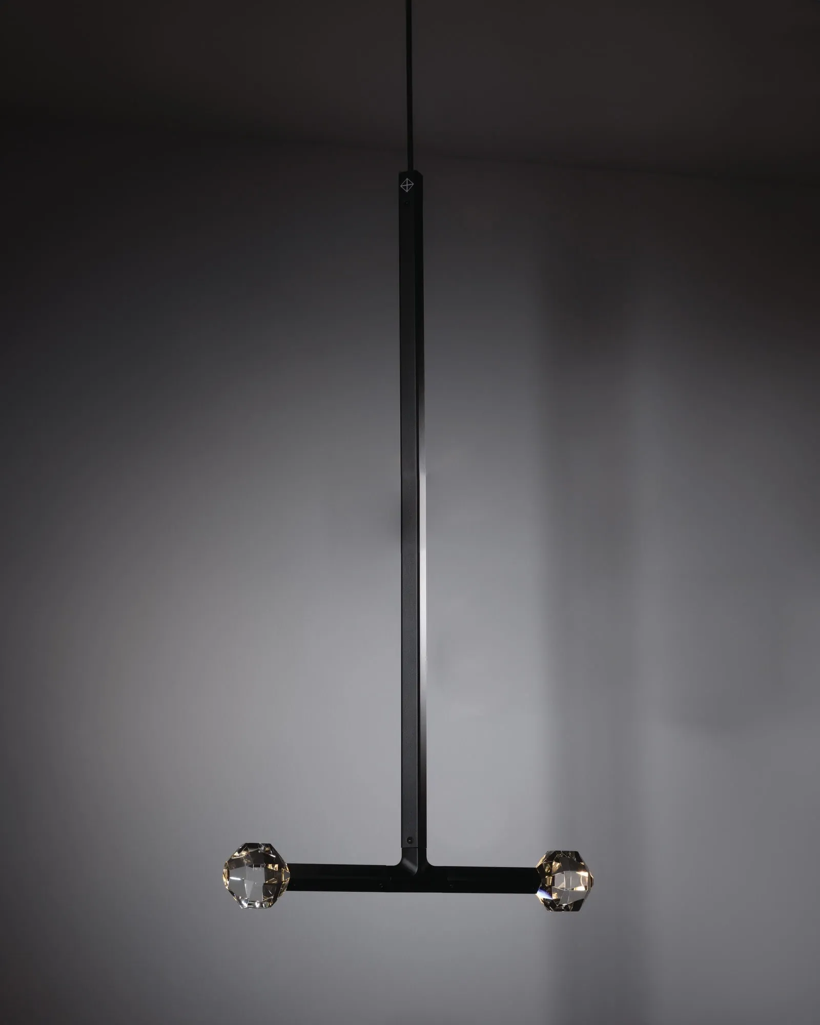 A JOULLE pendant in the studio: one stem ending in a crossbar with a crystal stone at each end