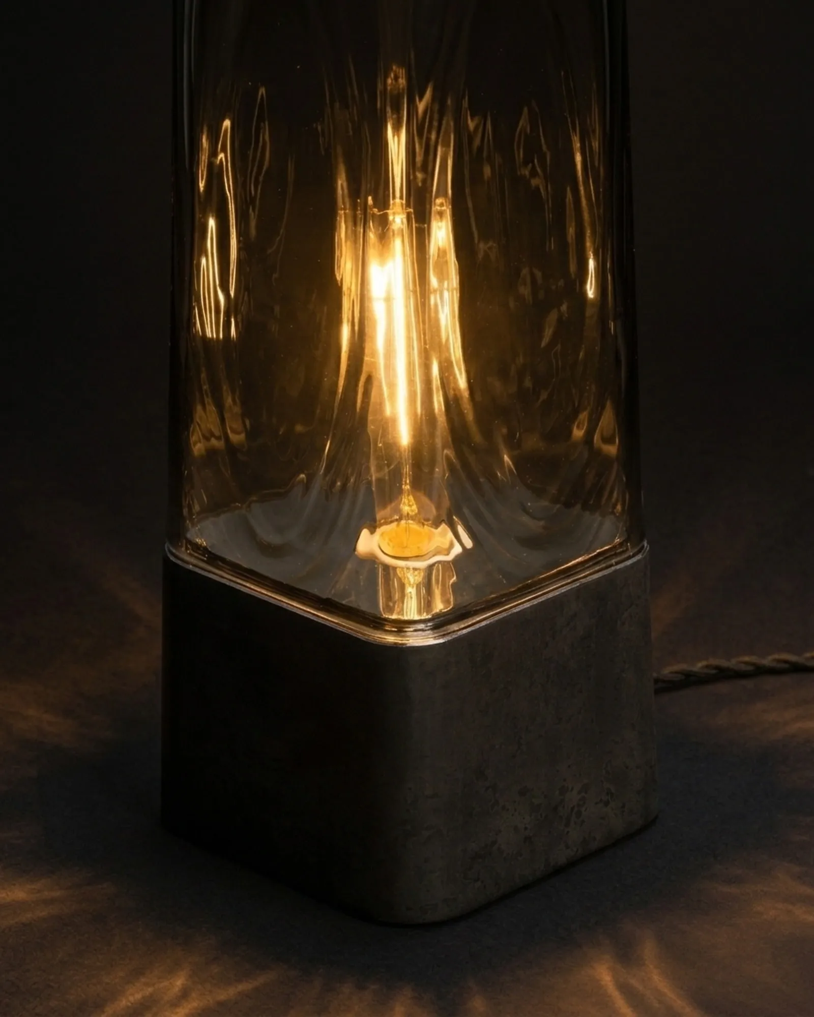 Faaro in clear glass, lit, close up against a dark wall