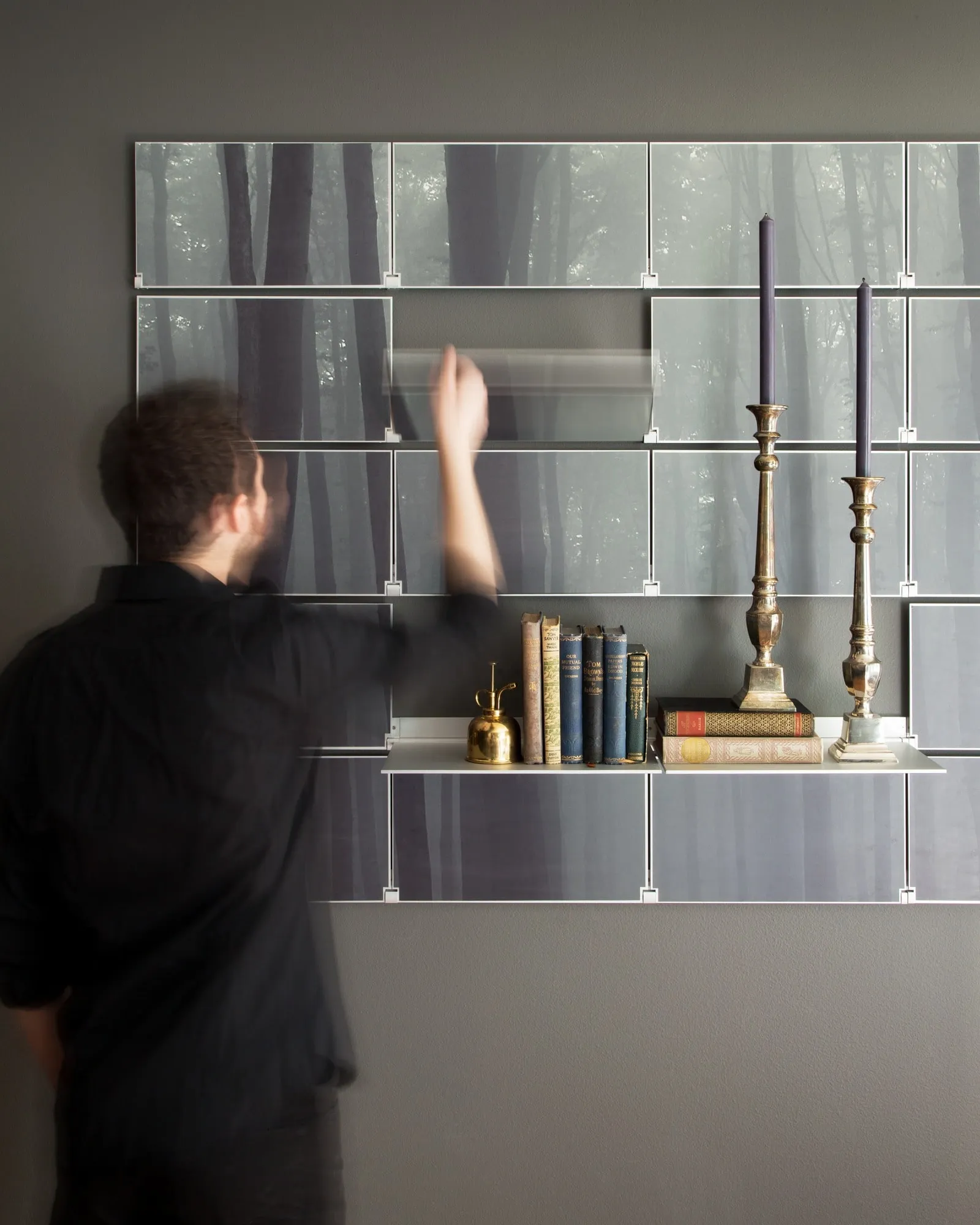 Folding down a shelf on a wall of Riveli Art Shelves printed with a misty forest