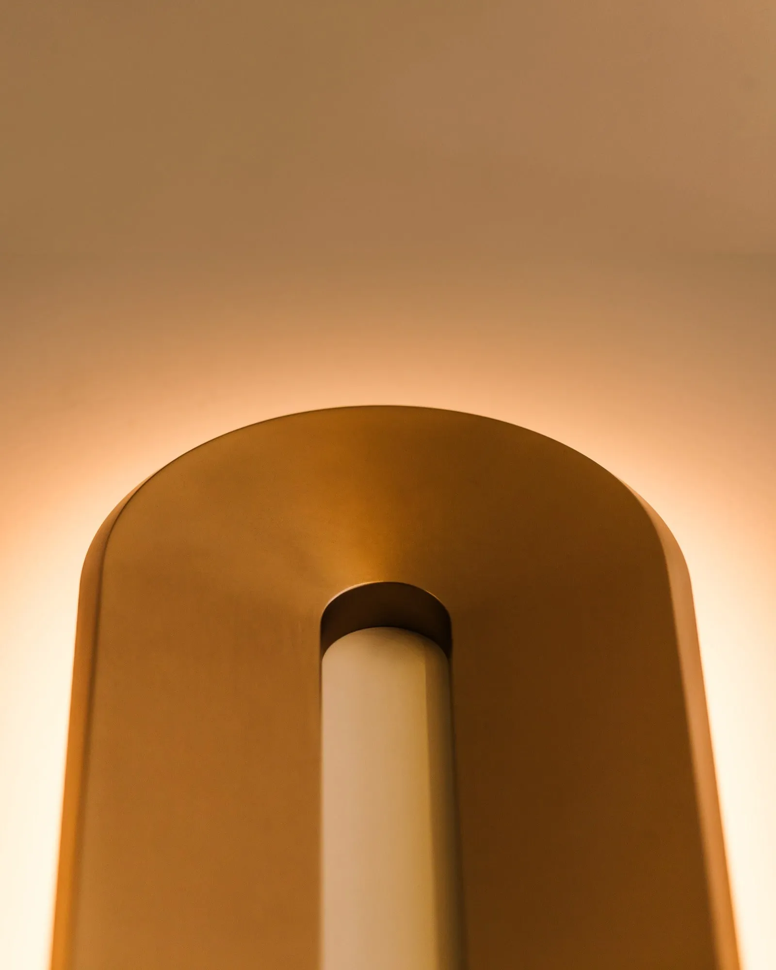 Void Sconce in brass, close up, its glow inside the ring
