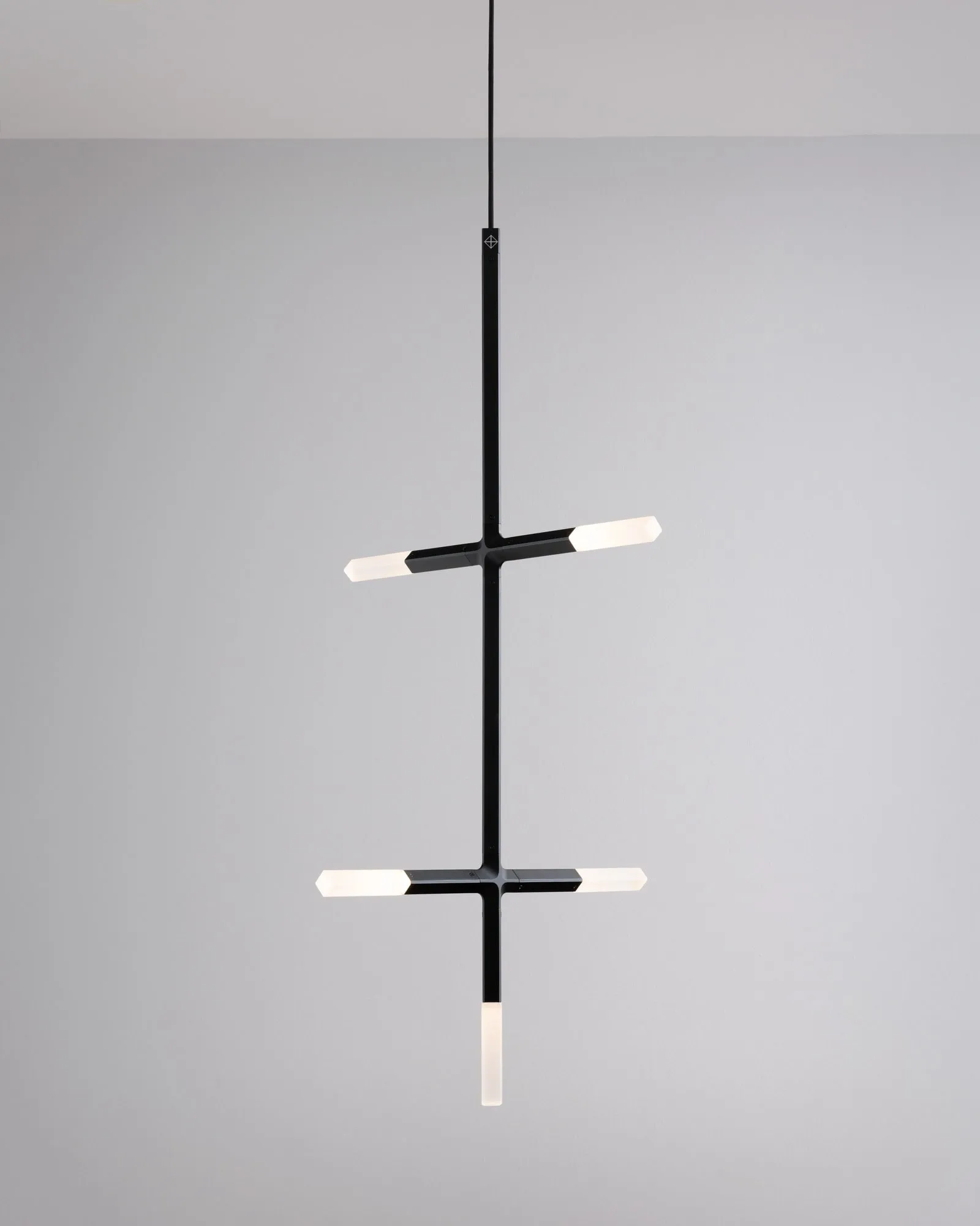 A JAX pendant in black with two arms of crystals against a pale grey wall