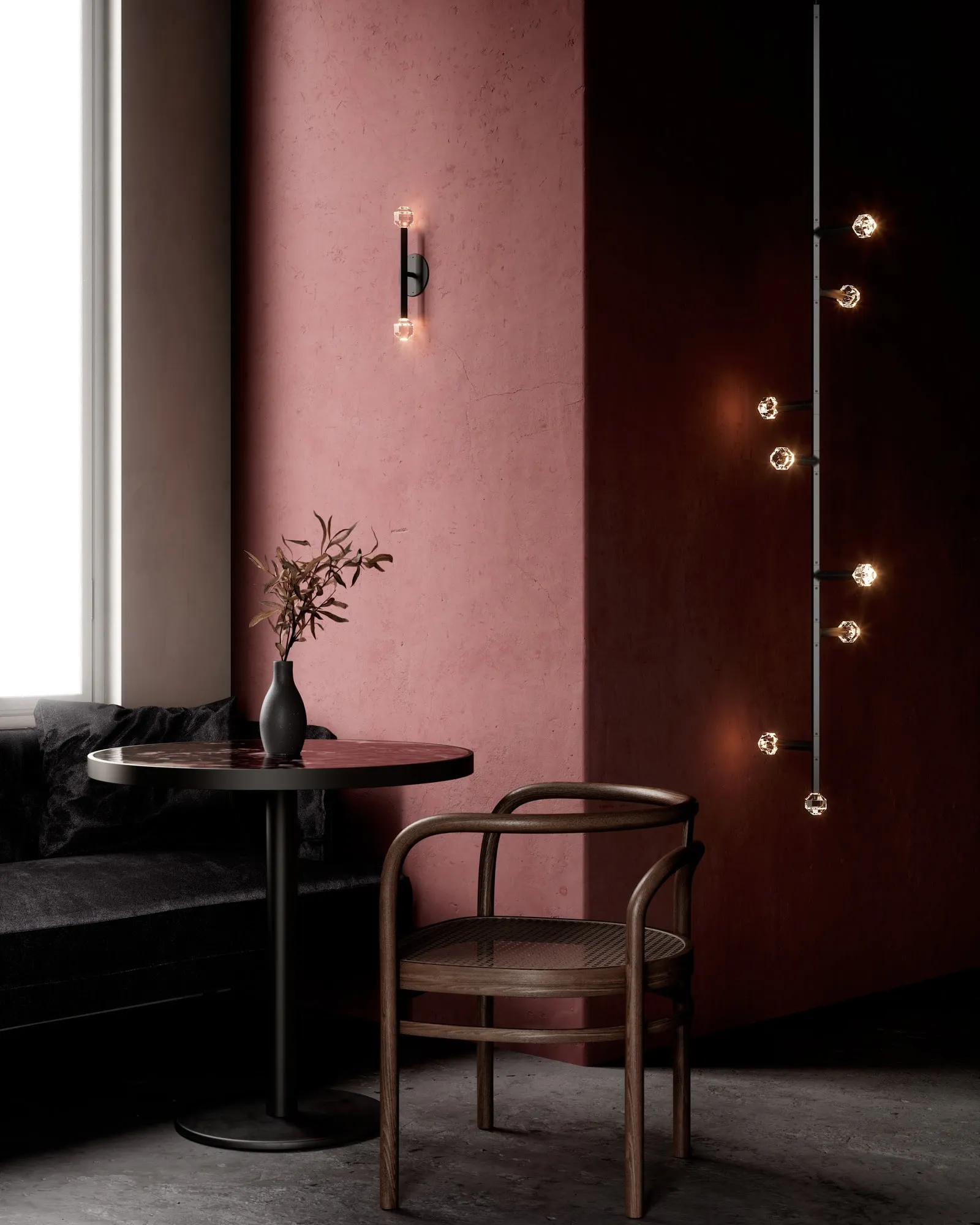 A JOULLE sconce and a tall JOULLE pendant against a rose plaster wall beside a café table