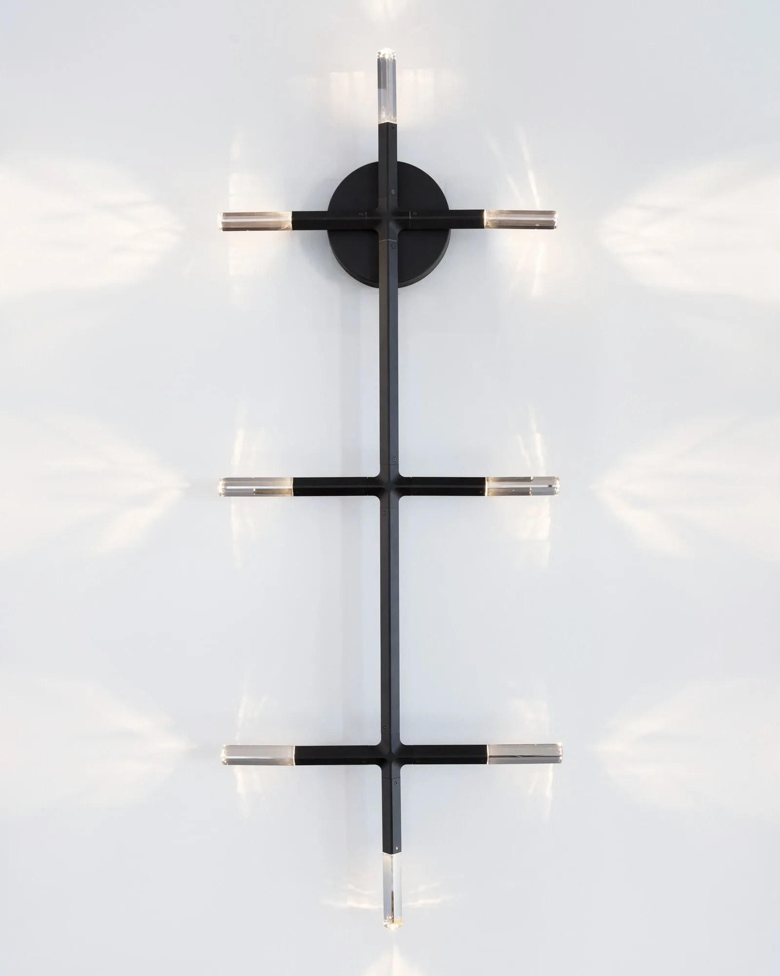 A JAX wall sconce with crystals casting patterns on a white wall
