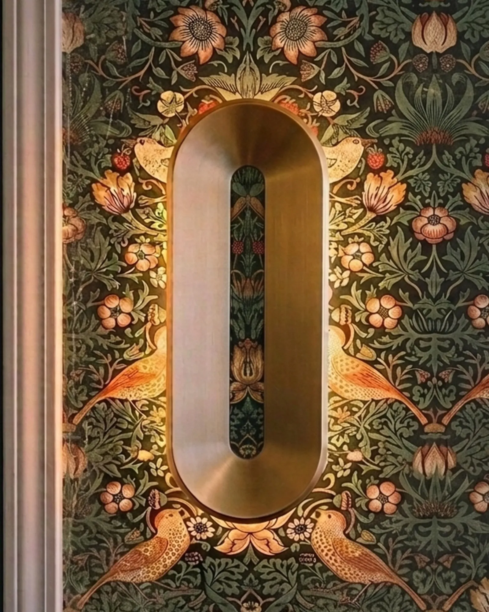 Void Sconce in brass on a patterned wallpaper, off, then lit as it reaches the middle of the screen