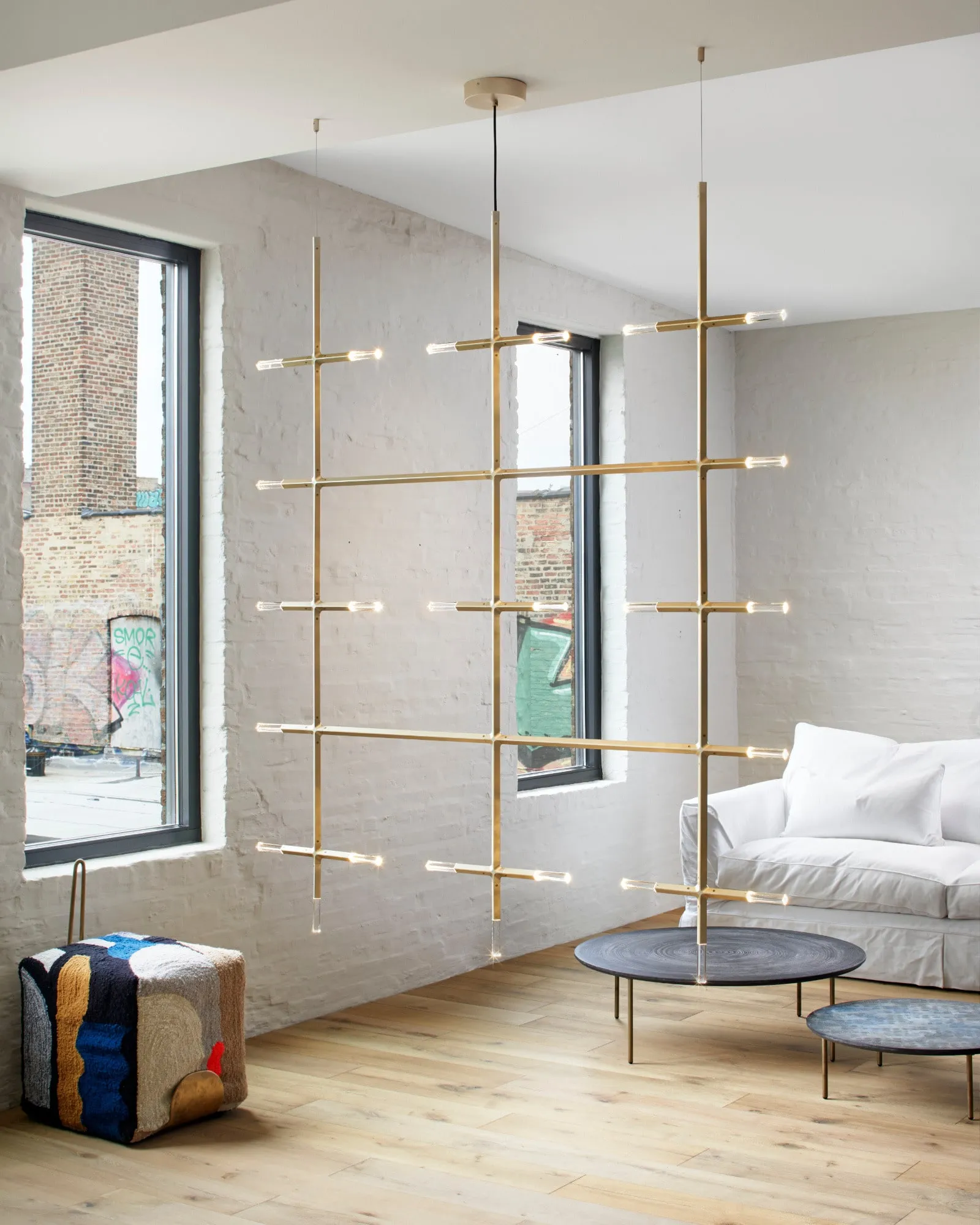 A JAX screen in Satin Brass in a sitting room by tall windows