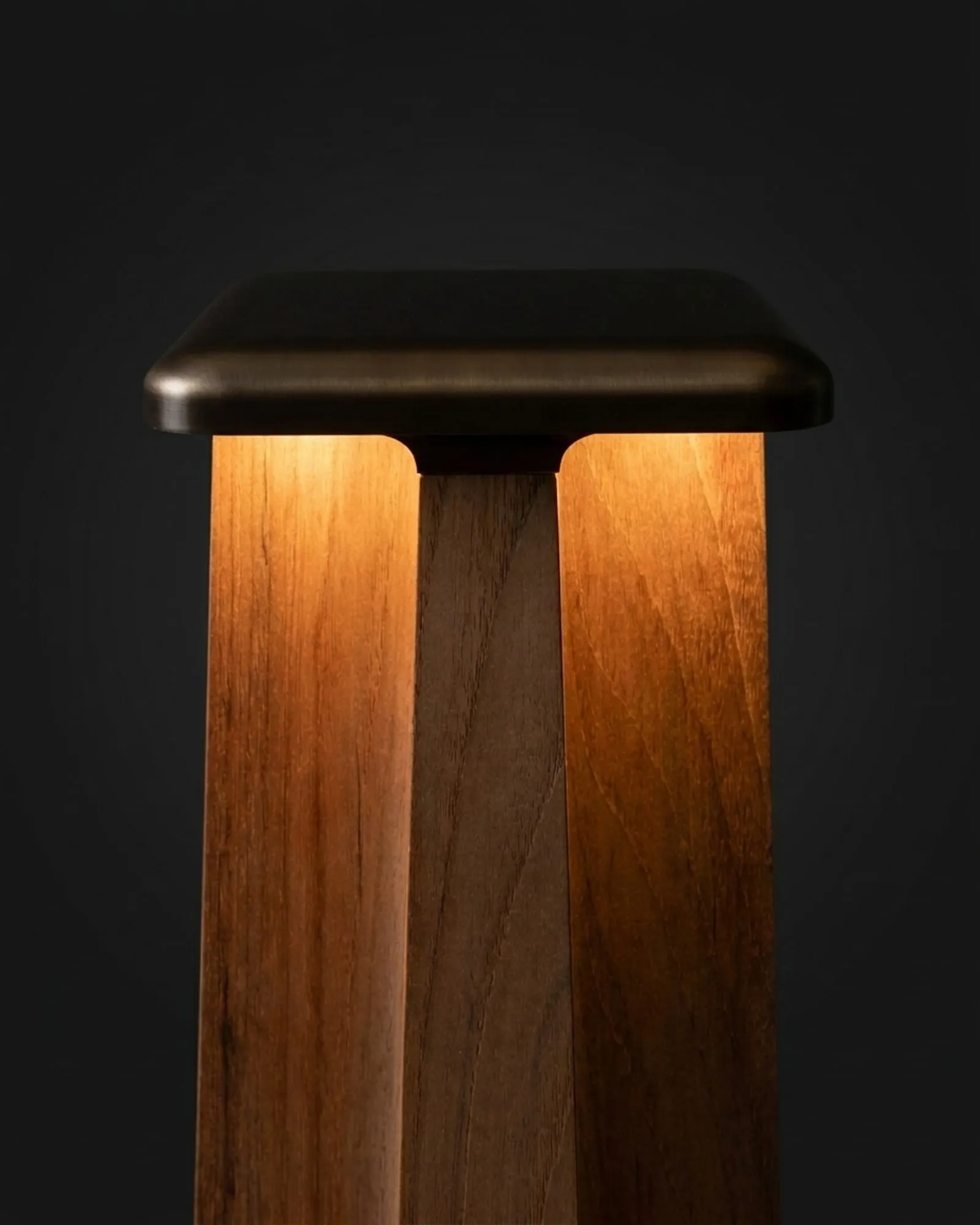 The top of a Totem Floor Lamp, lit from within the teak, close up