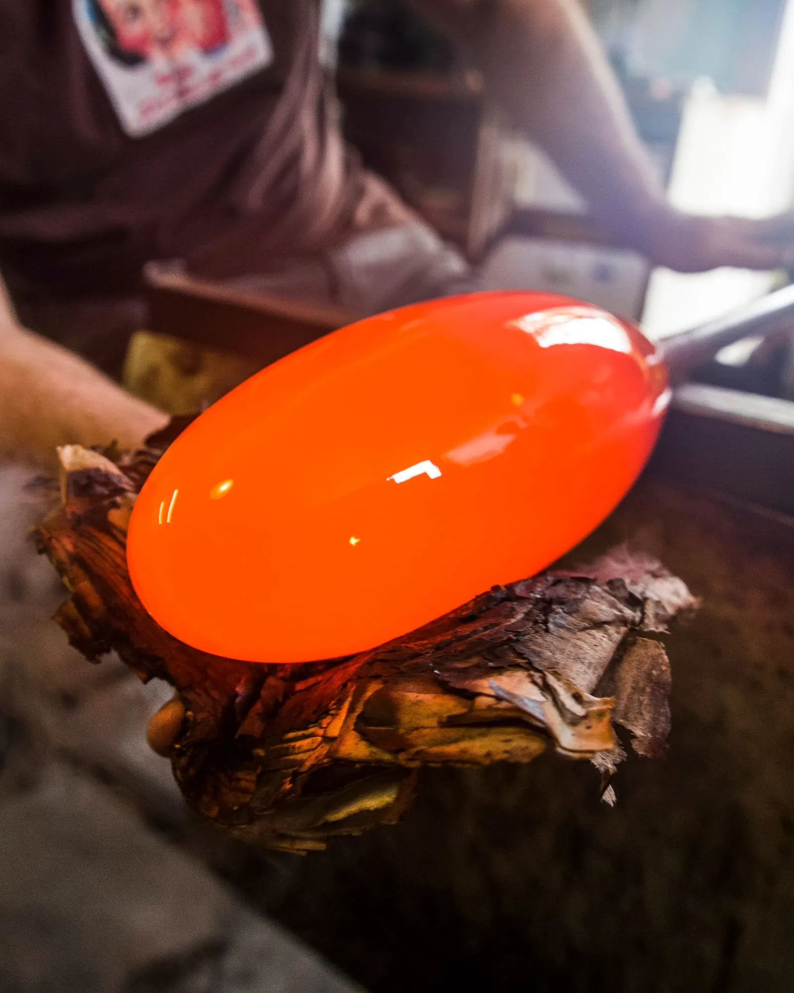 An Oona glass form being shaped on the blowpipe, glowing orange