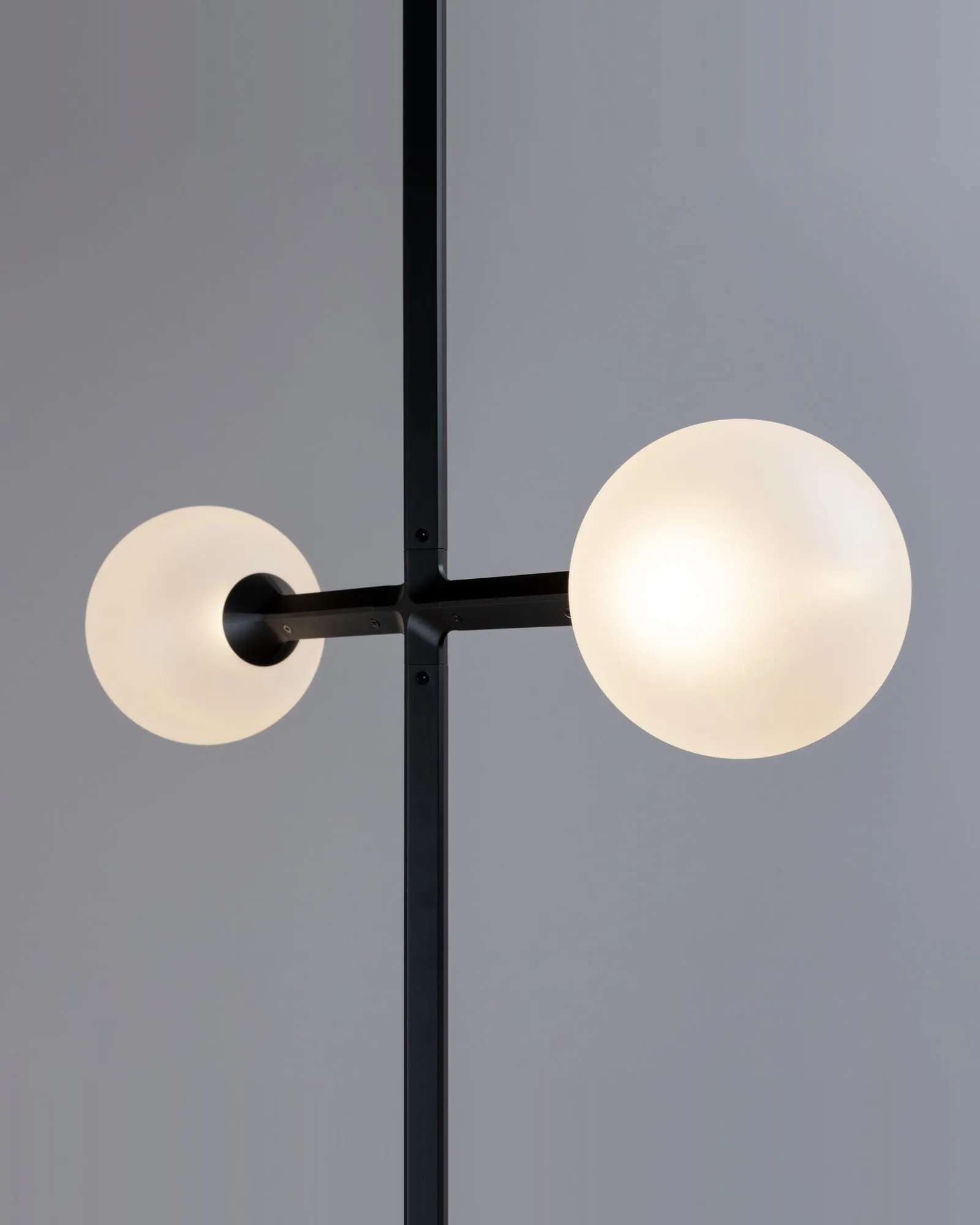 Two frosted JUNIP globes of different sizes on either side of a stem, close up