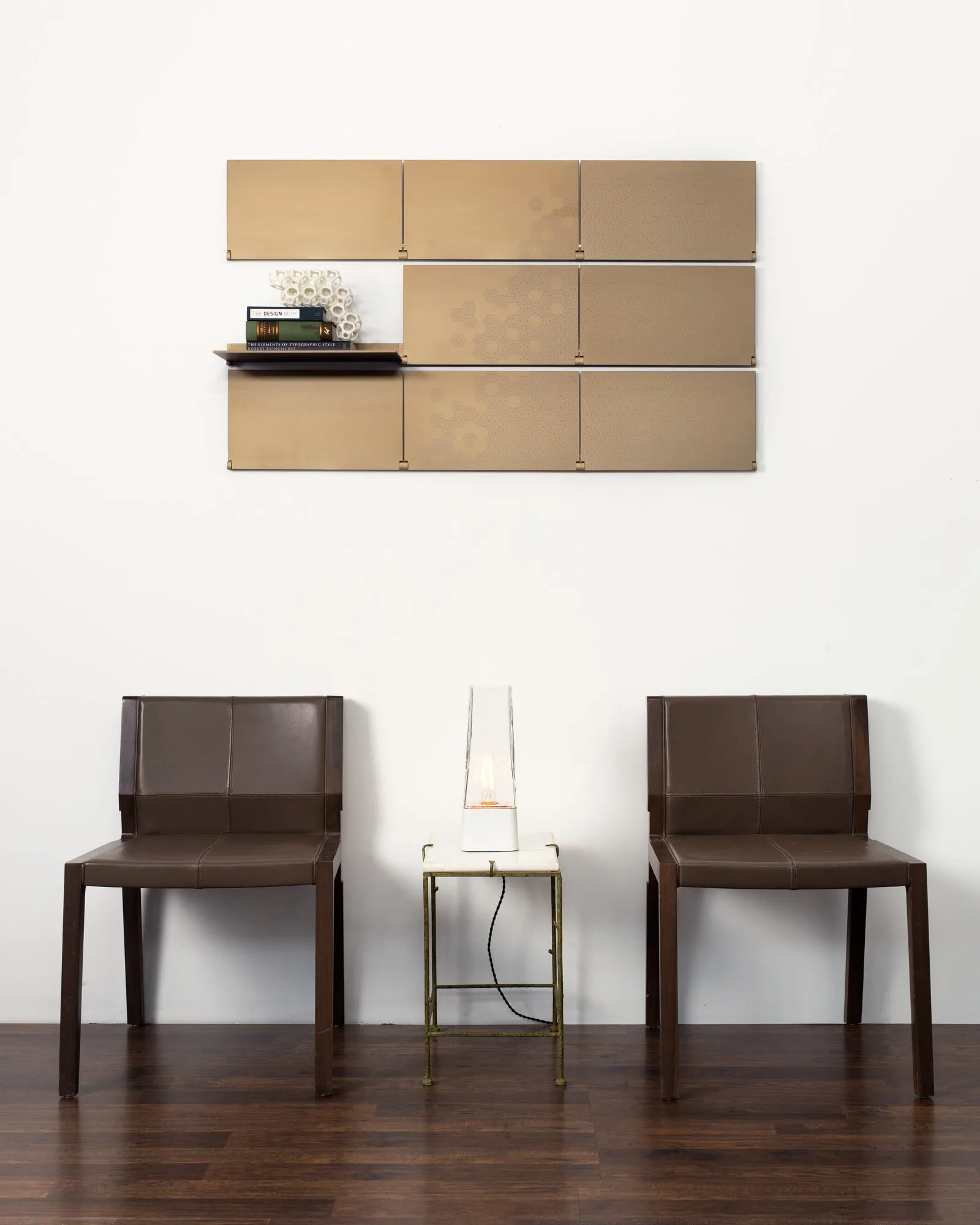Riveli Luxe Shelves in Aged Bronze above two chairs and a small table