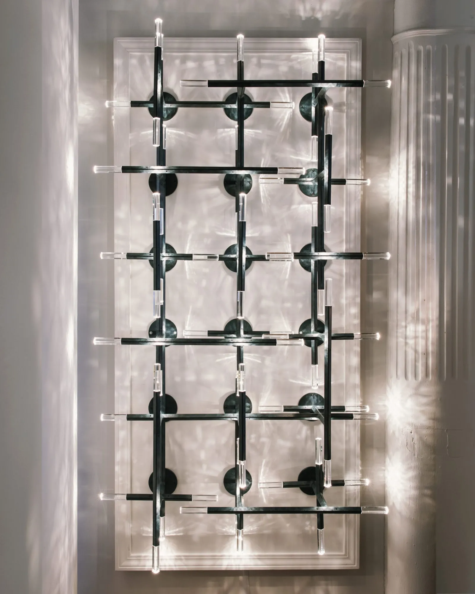 A JAX screen of black arms and crystal lights against a pale wall
