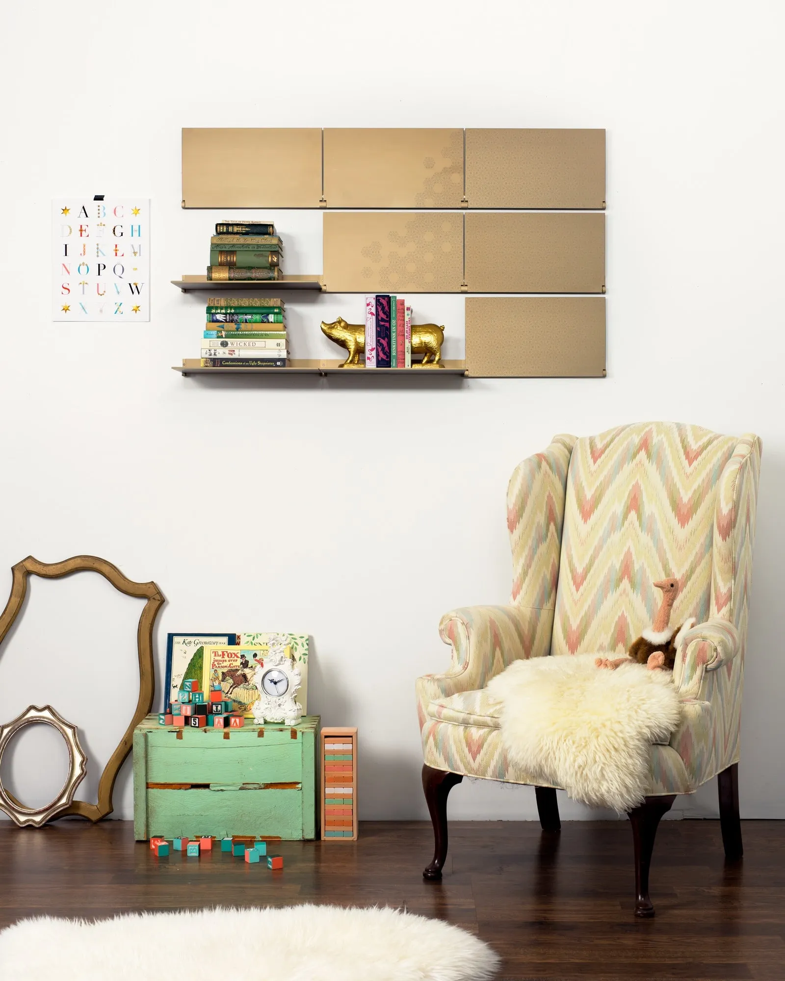Riveli Luxe Shelves in Aged Bronze, two shelves down with books, above a wing chair